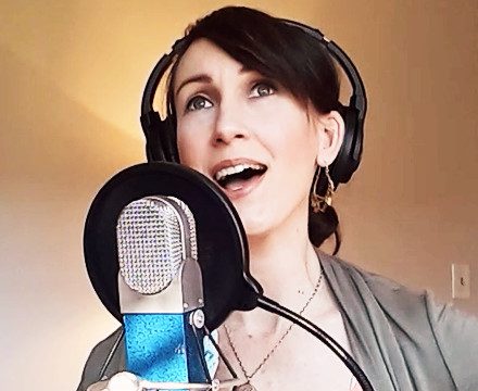 Katy Mantyk playing guitar and singing in the recording studio.